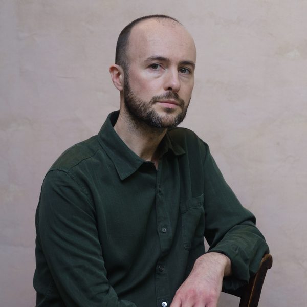 Edmund Finnis leans elbow on chair while looking to camera.