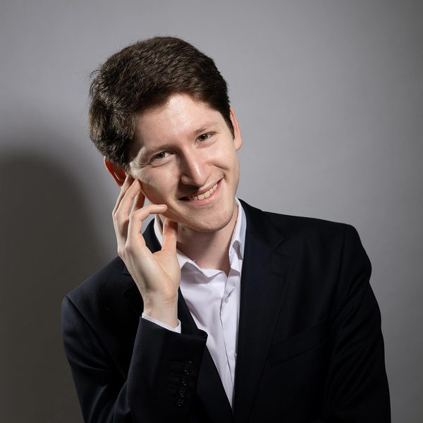 Emanuil Ivanov smiles to camera with one arm across the body and hand raised to face.