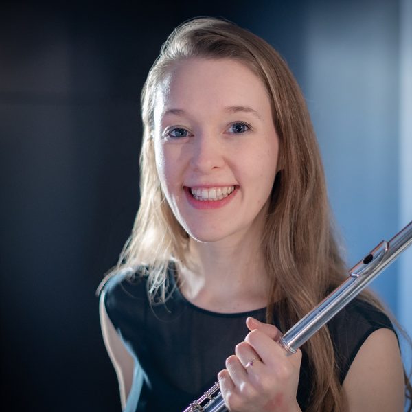 Portrait of Emma Halnan holding a flute, smiling to camera.