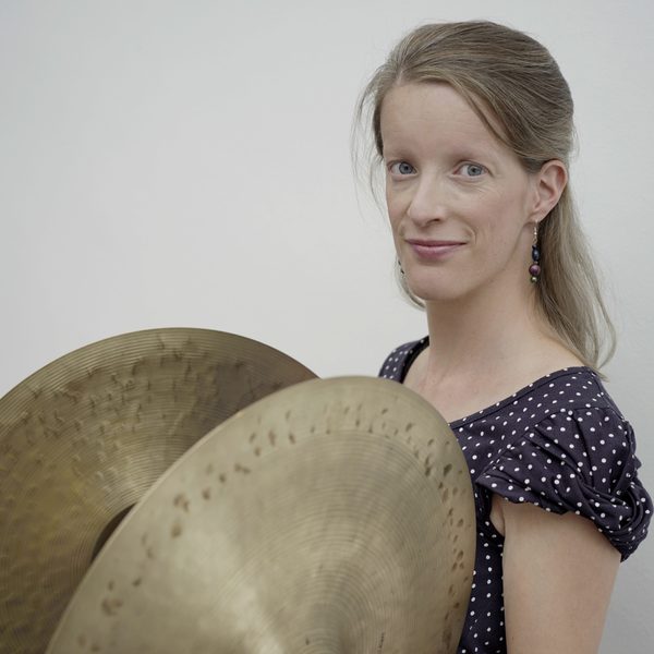 Erika Ohman holds cymbals, looking to camera.