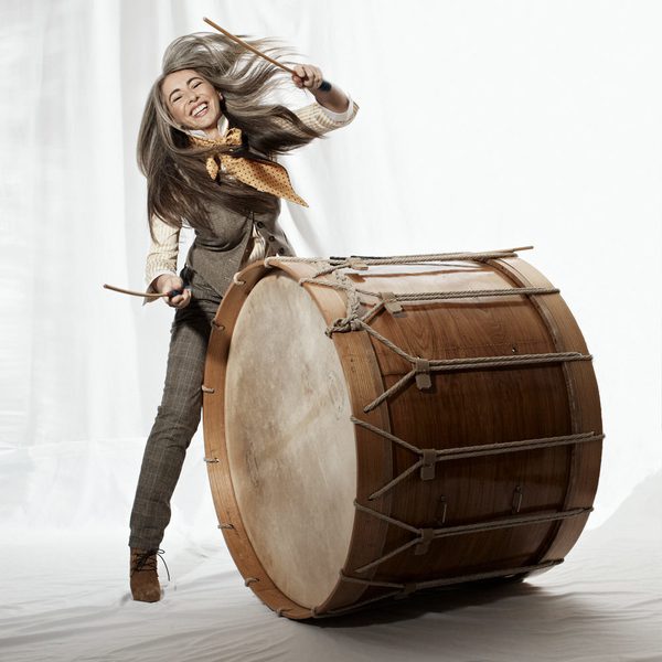 Evelyn Glennie strikes a giant tom drum, smiling