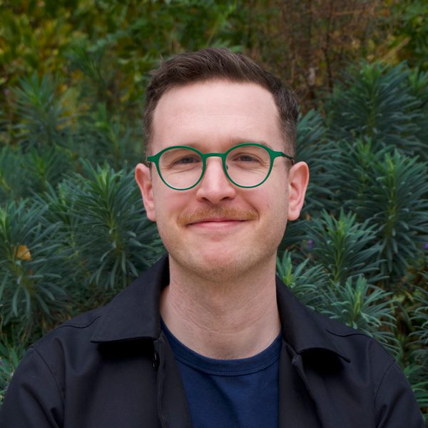 Portrait of Geoff King against a background of foliage.