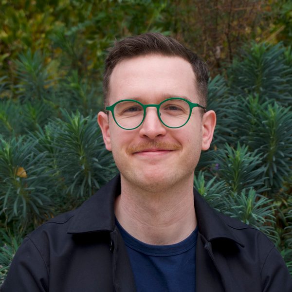 Portrait of Geoff King against a background of foliage.