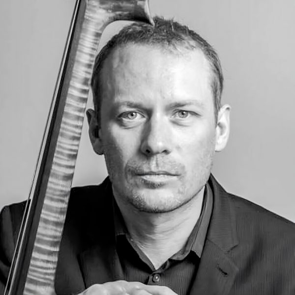 Portrait of Graham Mitchell facing camera, with double bass leaning against shoulder.