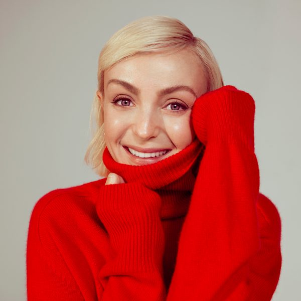 Portrait of Helen George wearing a red sweater.
