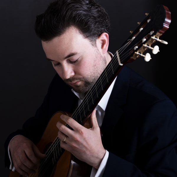 A classical guitarist performs and looks down pensively