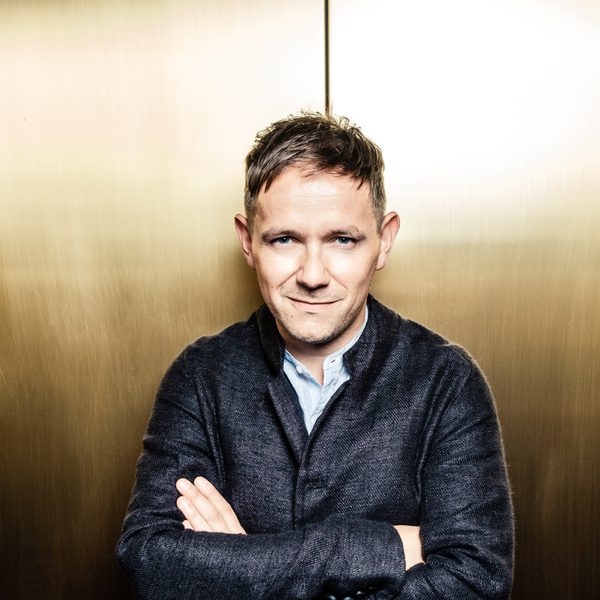 Iestyn Davies folds arms, looking to camera.