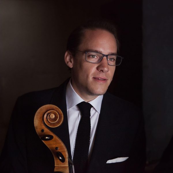 Portrait of a double bass player holding the neck of the instrument, looking off camera