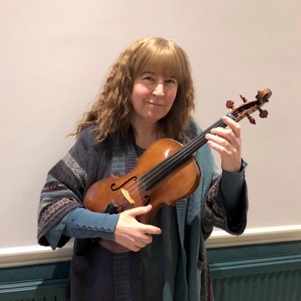 Jacky Woods holding a violin, smiling for camera.