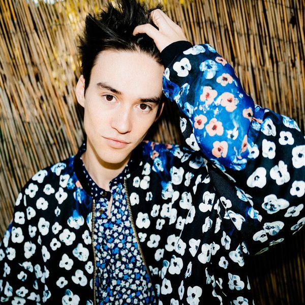 Jacob Collier Holds his hair, looking to camera.