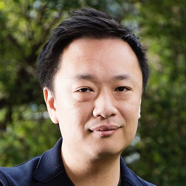 Portrait of James Cheung smiling for camera outside in a forested area.