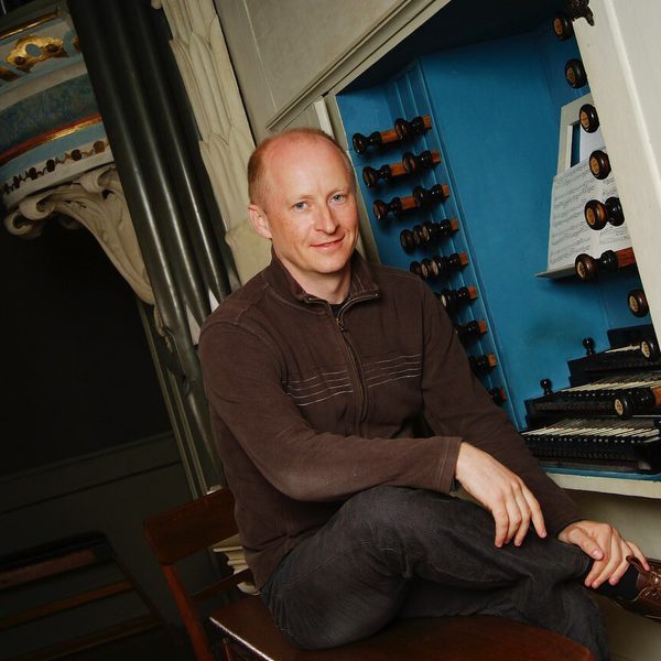 James Johnstone at an organ, smiling to camera.