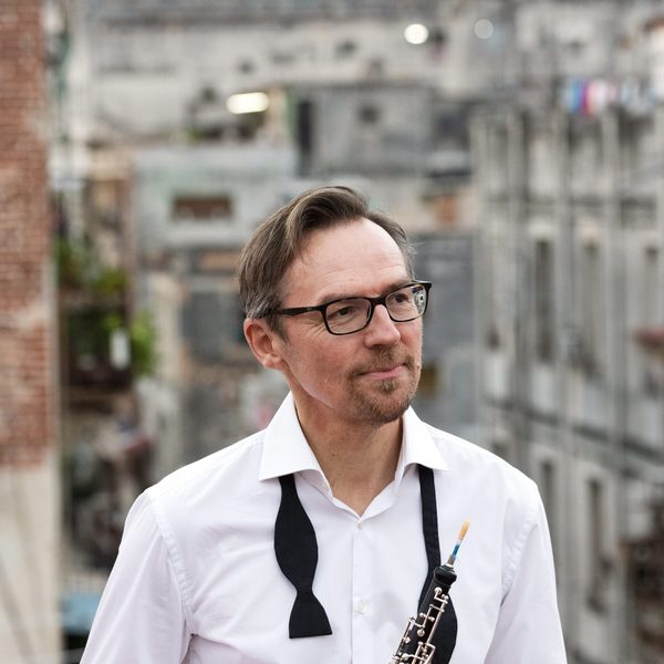 Jonathan Kelly stands posing on a rooftop with bowtie undone, looking into the distance.