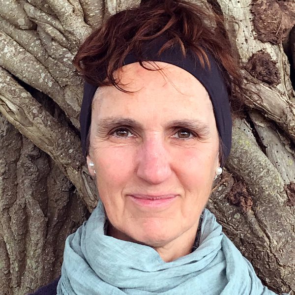 Close up of Judith Kleinman standing outdoors against a tree.