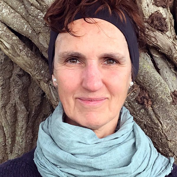 Close up of Judith Kleinman standing outdoors against a tree.