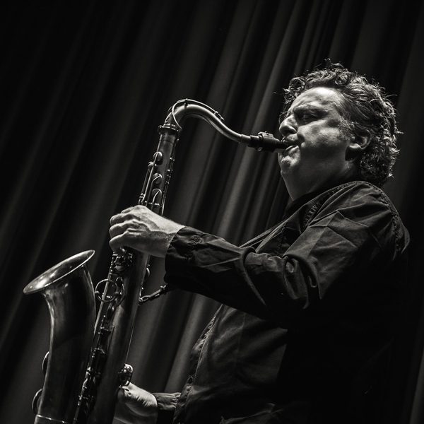 Side portrait of Julian Siegel playing saxophone on stage.
