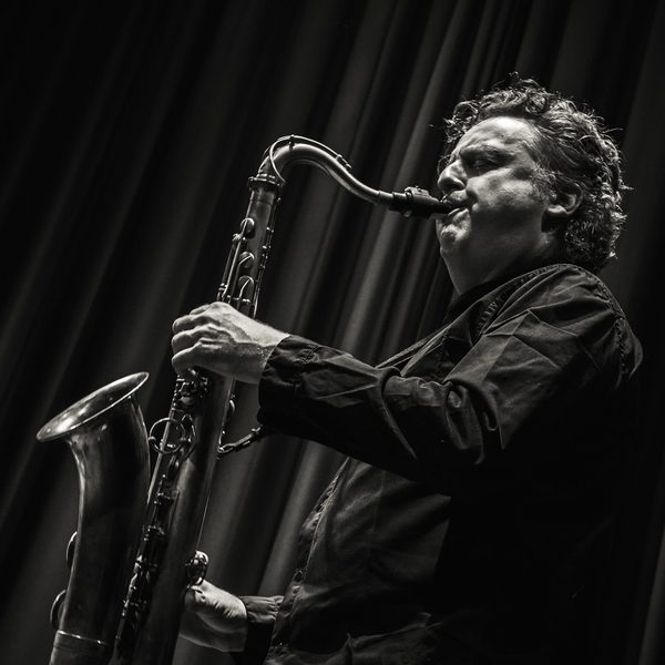 Side portrait of Julian Siegel playing saxophone on stage.