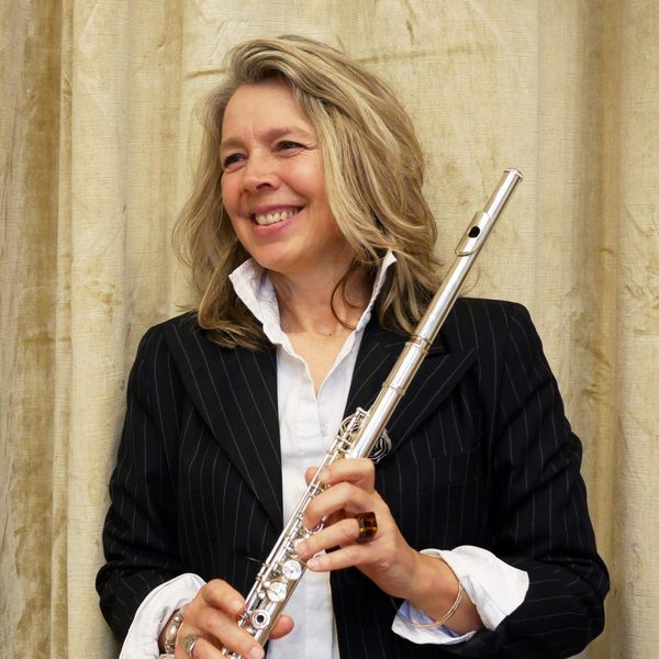 Karen Jones stands smiling and looking to the side while holding a flute