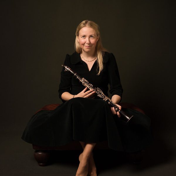 Katherin Spencer sits against a dark background holding a clarinet.