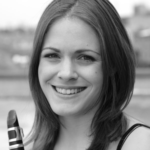 Close up of Katie Lockhart smiling for camera, holding a clarinet close to face.