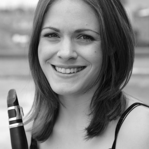 Close up of Katie Lockhart smiling for camera, holding a clarinet close to face.