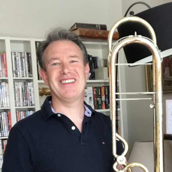 Keith McNicoll stands smiling with his trombone.