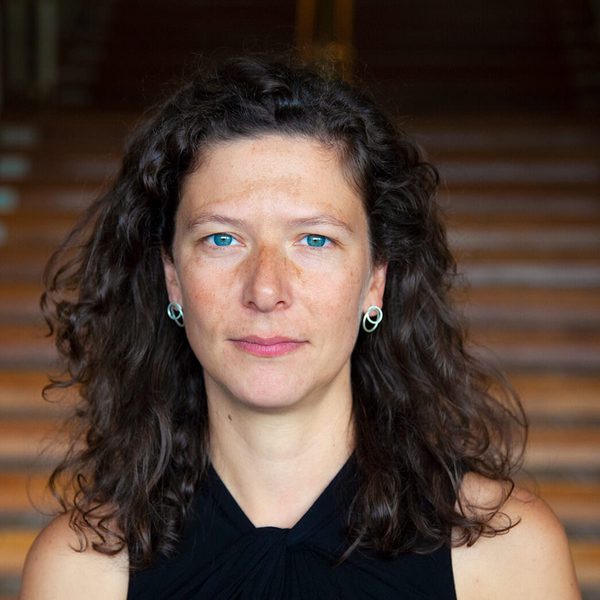 Kira Doherty stands at the bottom of a staircase, facing camera.
