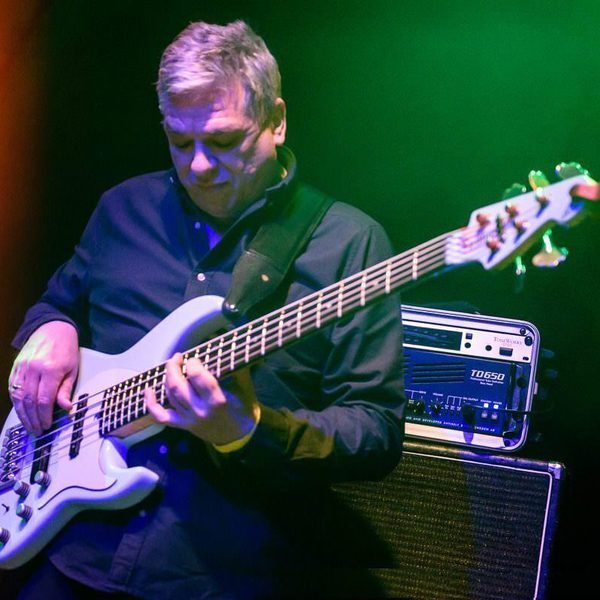 Laurence Cottle beneath stage lights, playing an electric bass guitar.