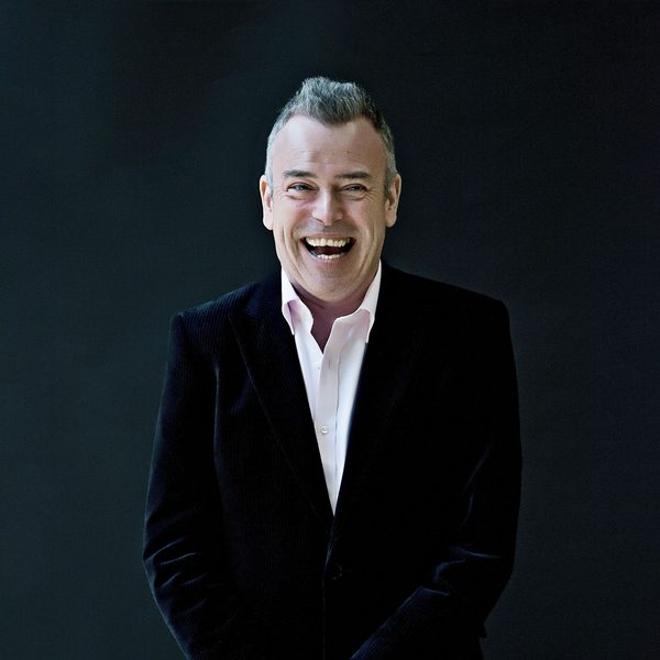 Malcolm Martineau smiling to camera against dark background.