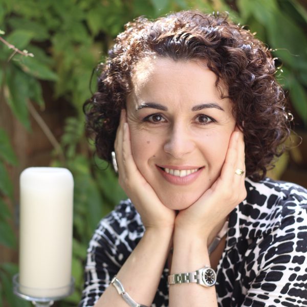Marie Vassiliou smiles to camera with face cradled in hands