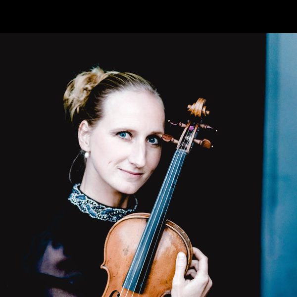 Marije Johnston looks to camera, holding violin.