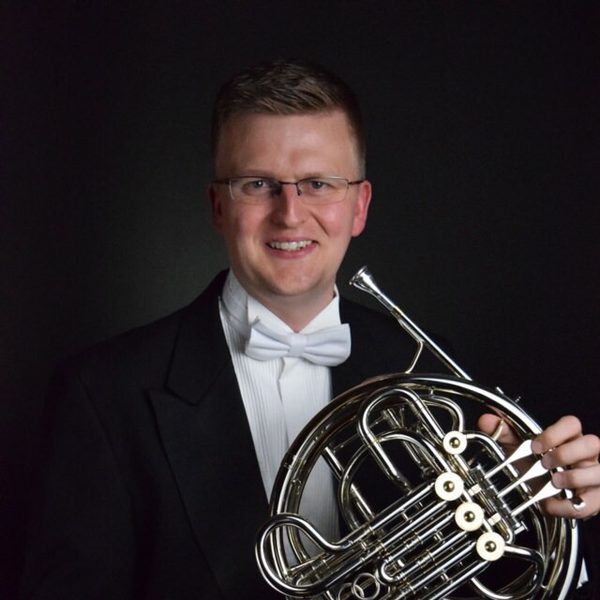 Mark Almond smiles to camera holding a horn.