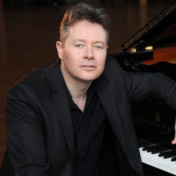 Mark Nixon sits at a piano keyboard, posing for camera.