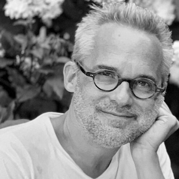 Martin Low smiles to camera, leaning head on hand.