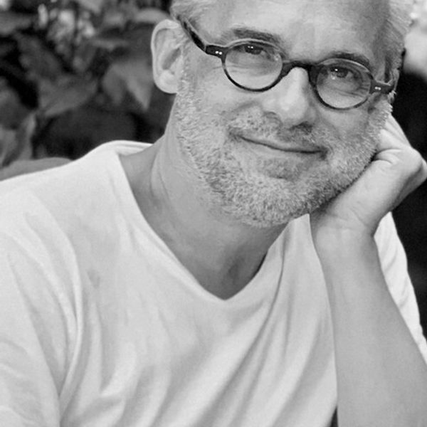 Martin Low smiles to camera, leaning head on hand.