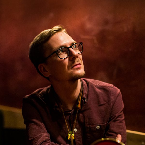Matt Anderson poses for headshot with trombone, staring into the distance
