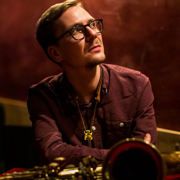 Matt Anderson poses for headshot with trombone, staring into the distance
