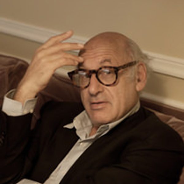 Michael Nyman sits down, looking to camera.