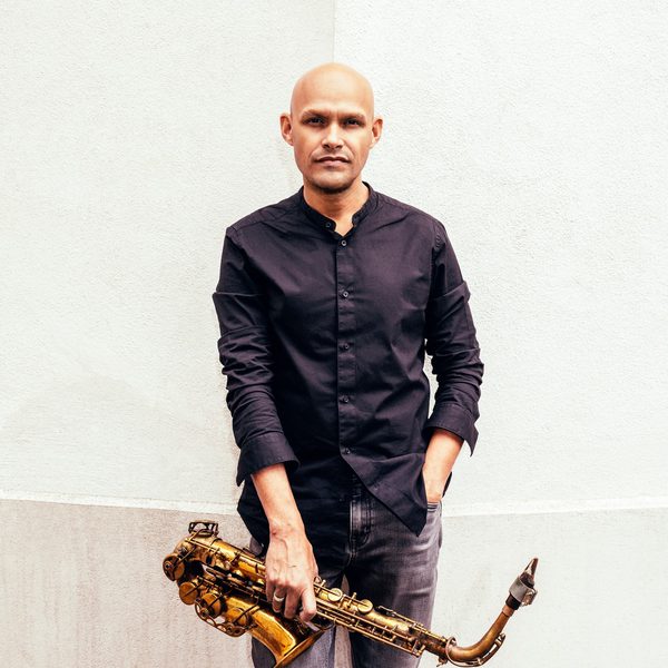 Miguel Zenon stands hand in pocket, holding a saxophone.