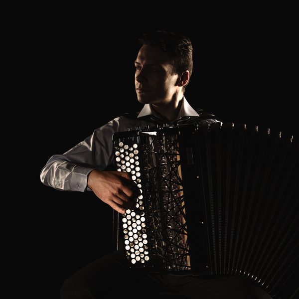 Accordionist Milos Milivojevic plays in high contrast light.