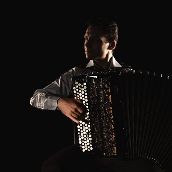 Accordionist Milos Milivojevic plays in high contrast light.
