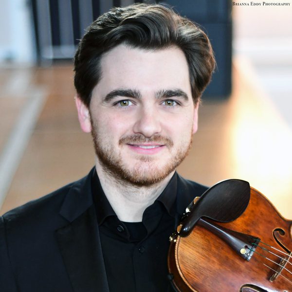 Nathaniel Anderson-Frank smiles to camera, holding a violin.