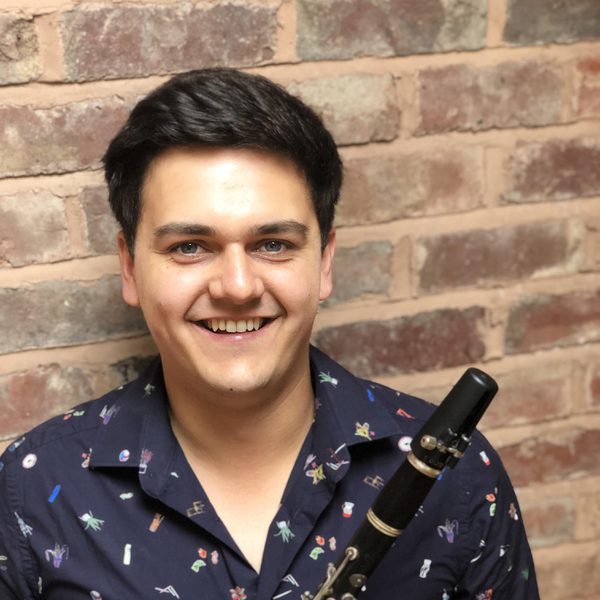 Oliver Janes smiles to camera, holding clarinet.