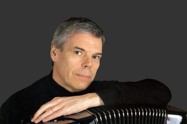 Owen Murray faces camera, with arm resting on top of an accordion.