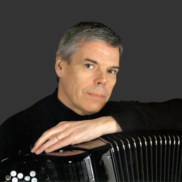 Owen Murray faces camera, with arm resting on top of an accordion.