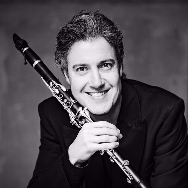 Patrick Messina poses for camera, holding a clarinet.