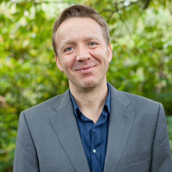 Paul Rissmann smiles to camera, outside.