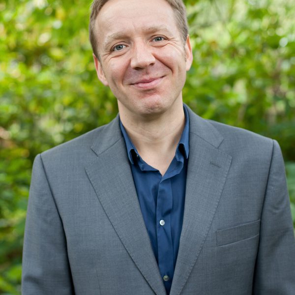 Paul Rissmann smiles to camera, outside.