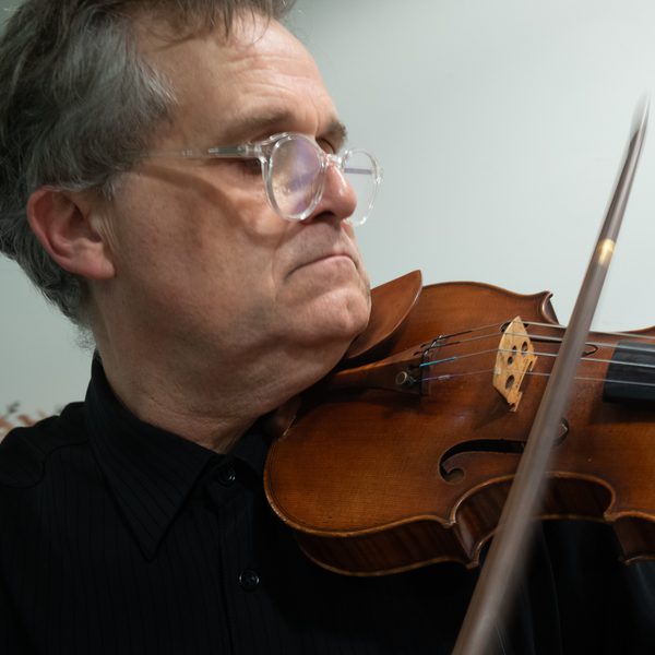 Close up of a man playing a violin.