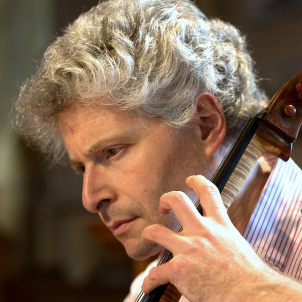 Close up of Robert Max mid-performance, playing a cello.